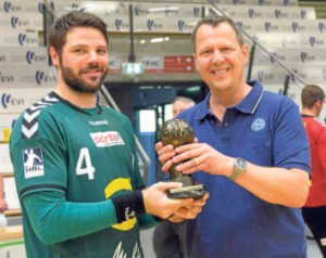Kreiswohnbau-Geschäftsführer Matthias Kaufmann überreicht den Siegerpokal an GWD-Kapitän Moritz Schäpsmeier.